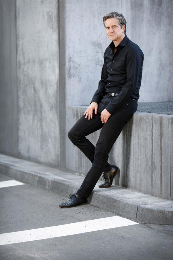 Der Jazz Künstler Rossi lehnt lässig an einer Wand