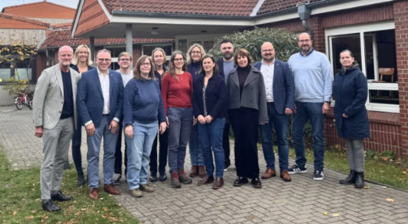 Eine Gruppe von Menschen steht vor einer Schule wegen Laatzen Offener Ganztag ab August 2026   AWO Region Hannover und Stadt Laatzen.